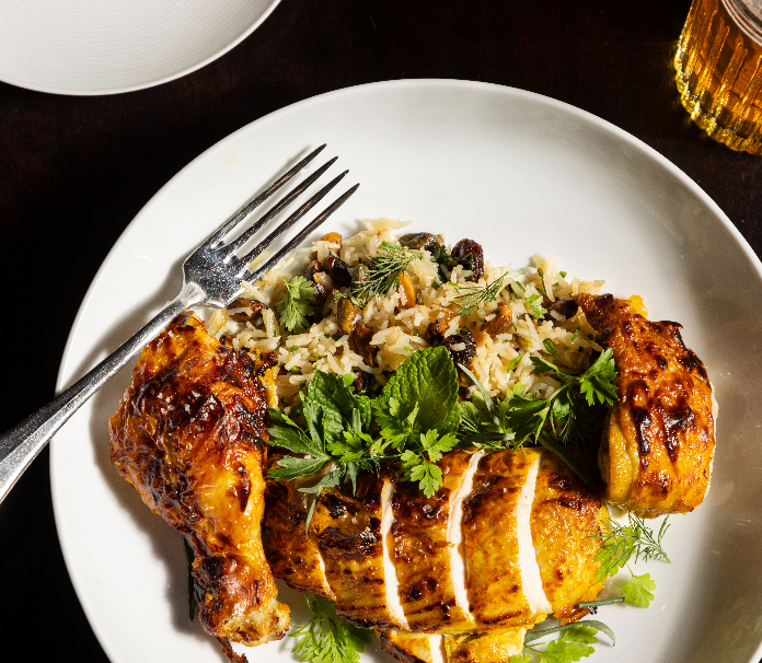Tandoori chicken with herbed rice and fresh cilantro on a white plate.